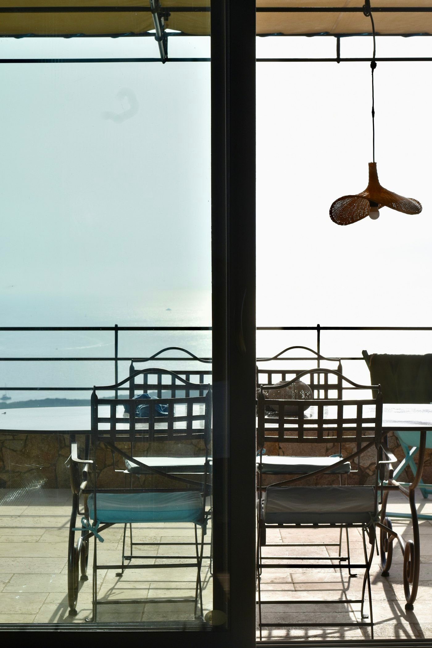 A shaded terrace with the sea beyond the railing