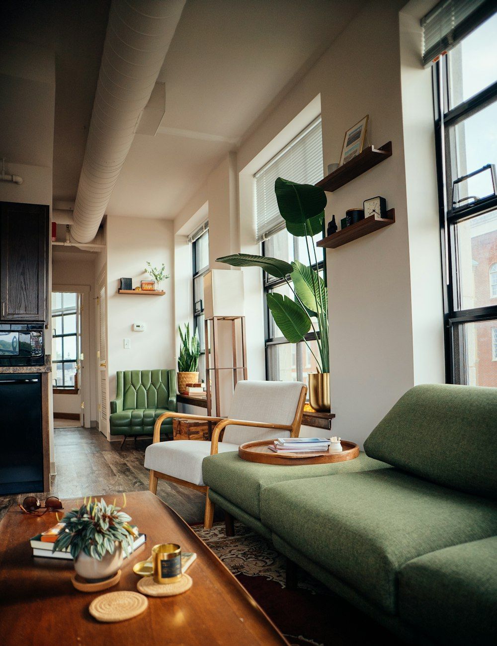 A loft living room with tall windows and a green sofa