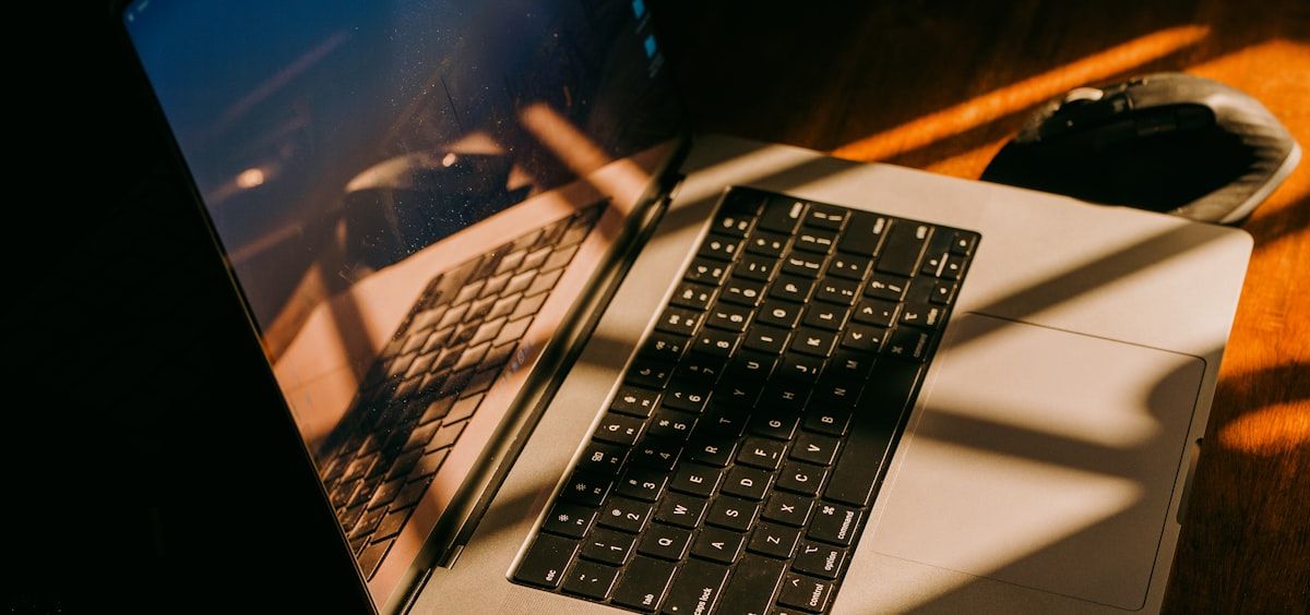 Low evening sun falling across an open laptop on a wooden desk