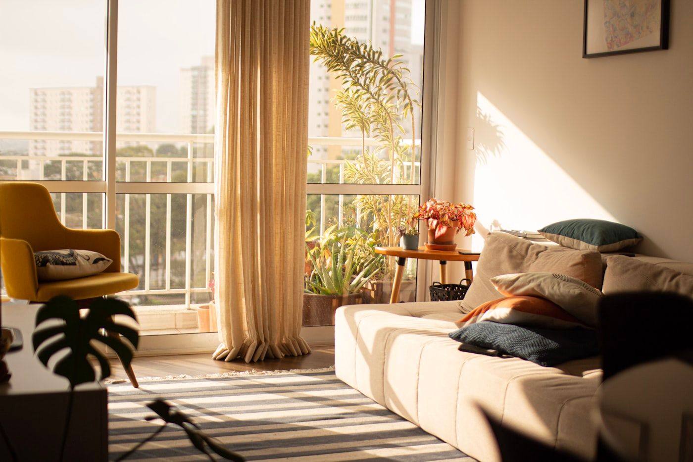 A sunlit living room opening onto a planted balcony